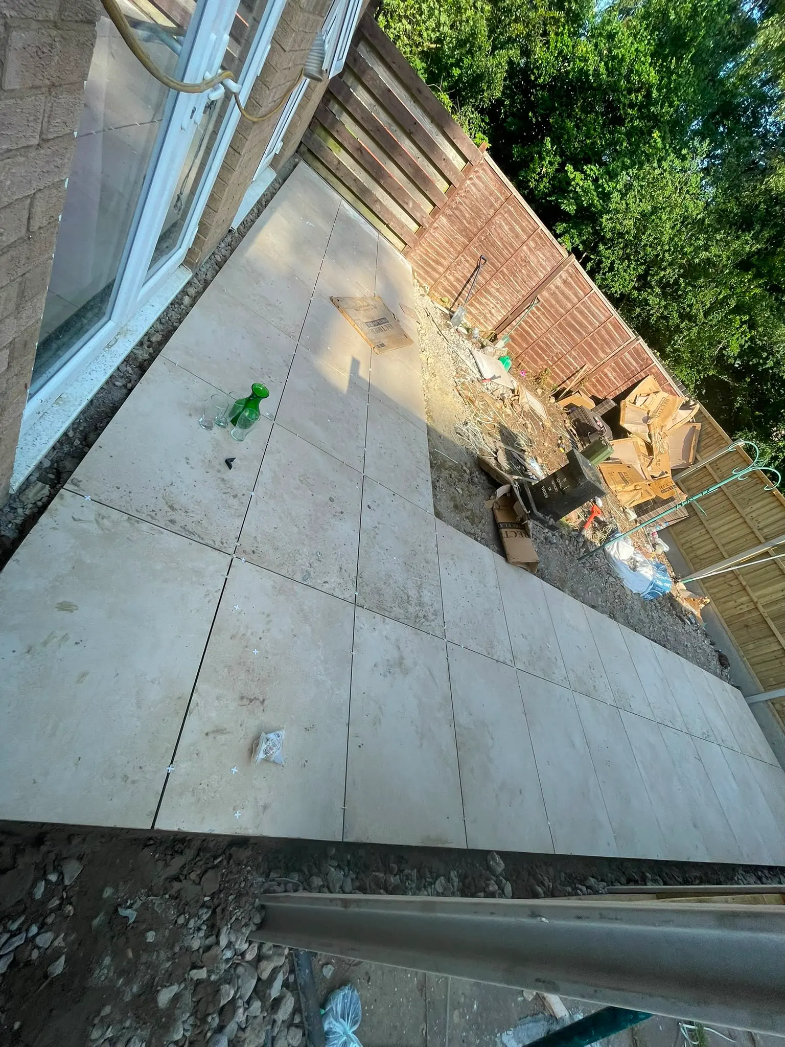 Work-in-progress porcelain patio installation showing paving slabs and tile spacers in a Northampton garden