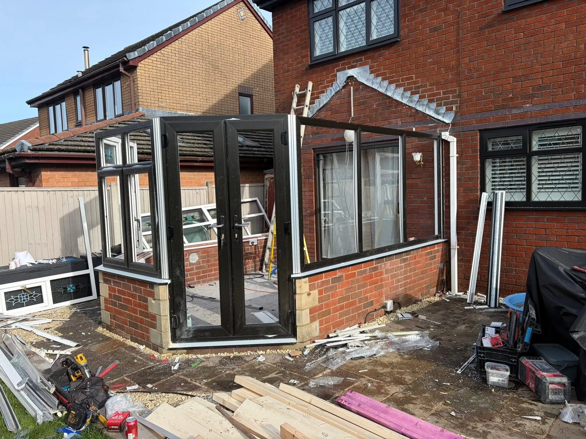 Black uPVC conservatory frames being installed on a brick base for a solid roof conversion project in Lancashire.