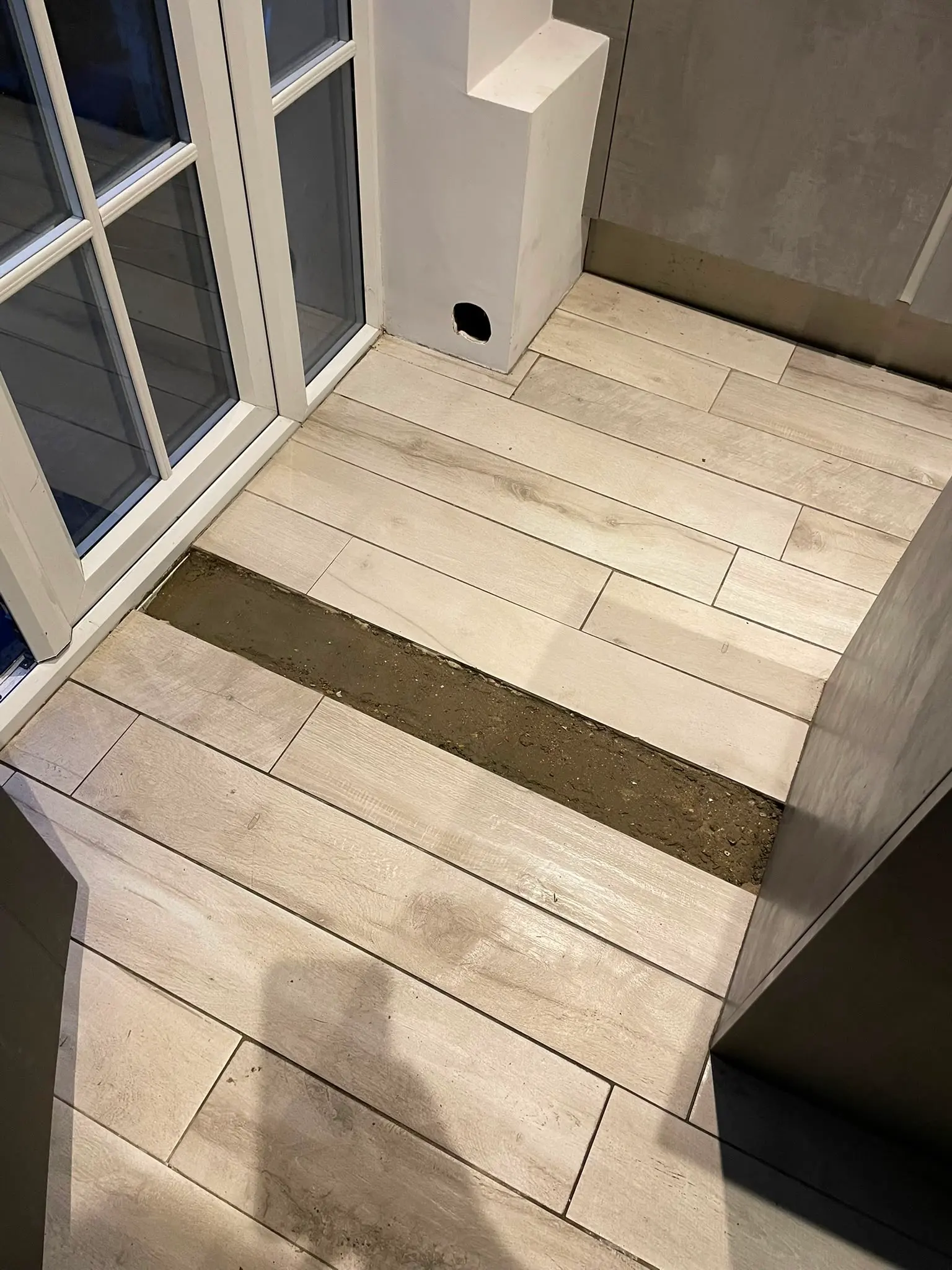 Indoor tiled floor excavated for new drainage and pipework installation