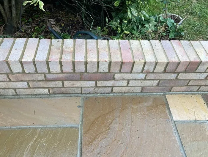 Close-up of a new brick garden wall and a natural stone patio in a garden.