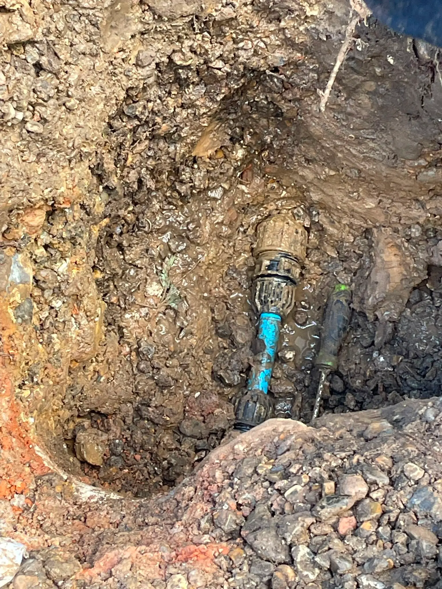 Underground blue water pipe exposed in a dug trench for repair