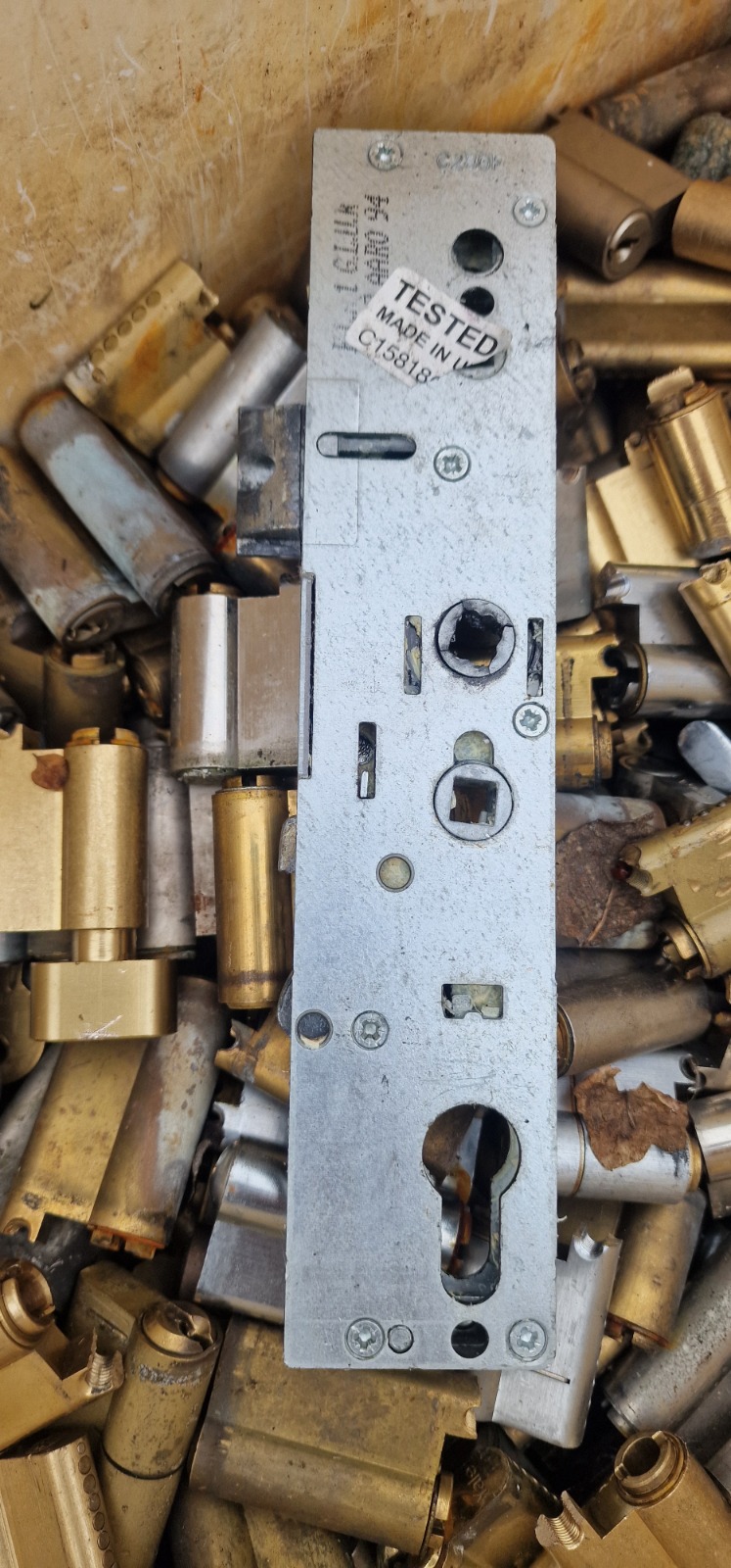 A pile of discarded door lock cylinders and a uPVC multi-point lock gearbox.