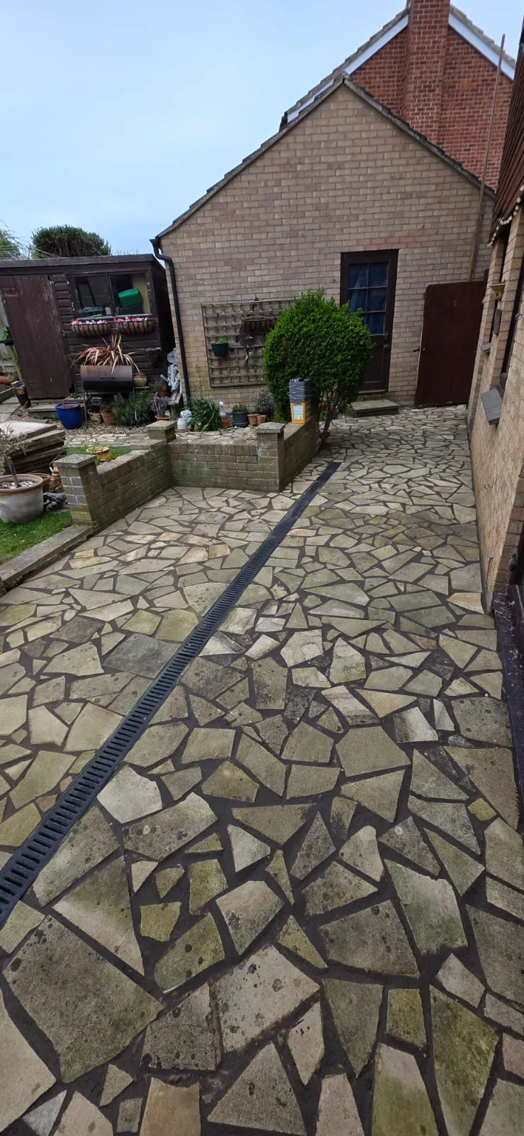 Natural stone crazy paving patio with a linear channel drain in a residential back garden