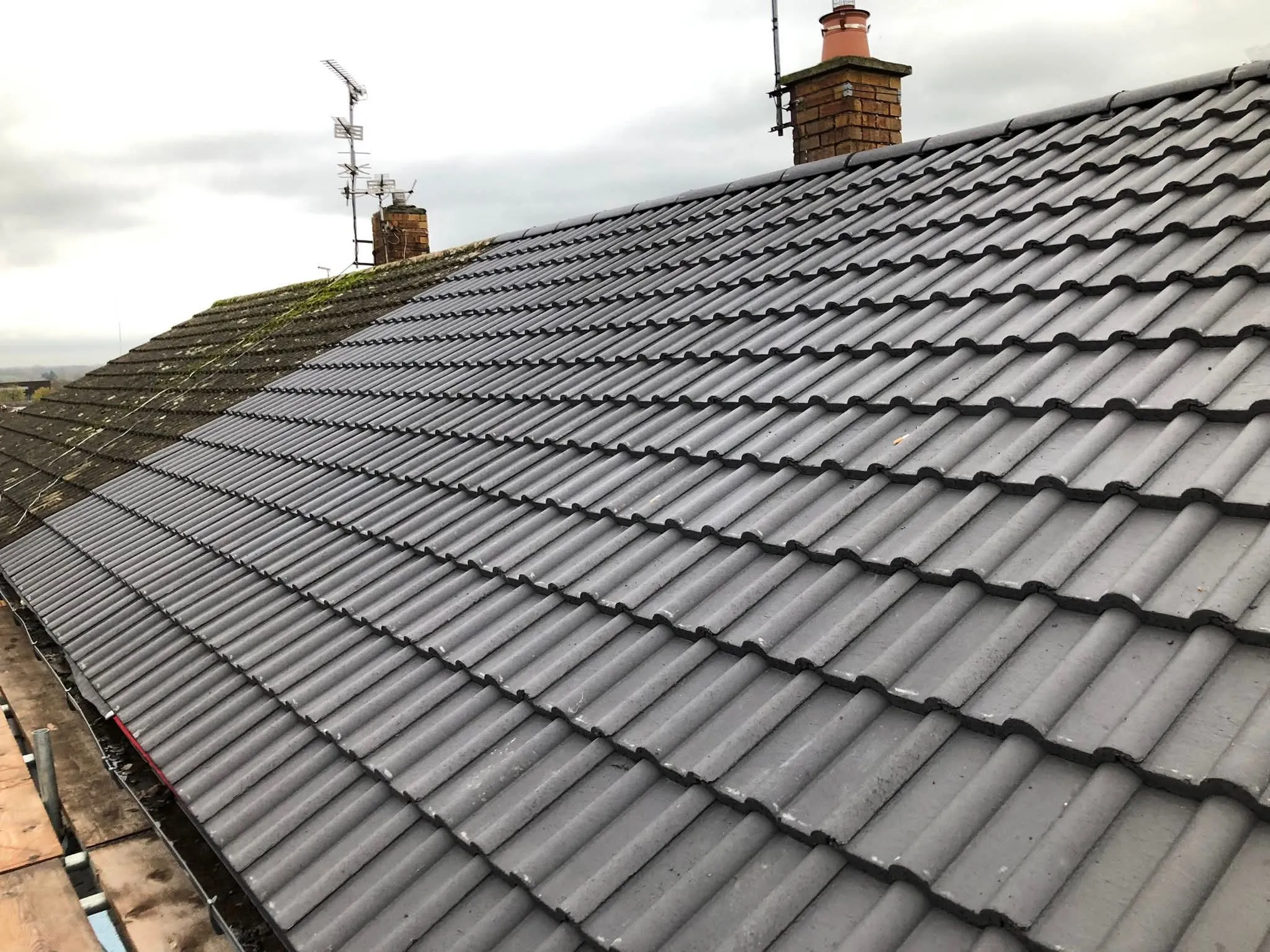 Professional new grey concrete tile roof installation on a residential property