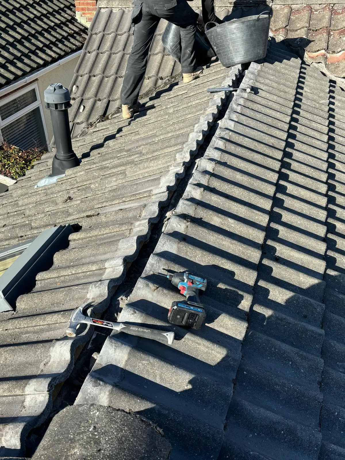 A professional roofer performing tiled roof repairs on a residential property.