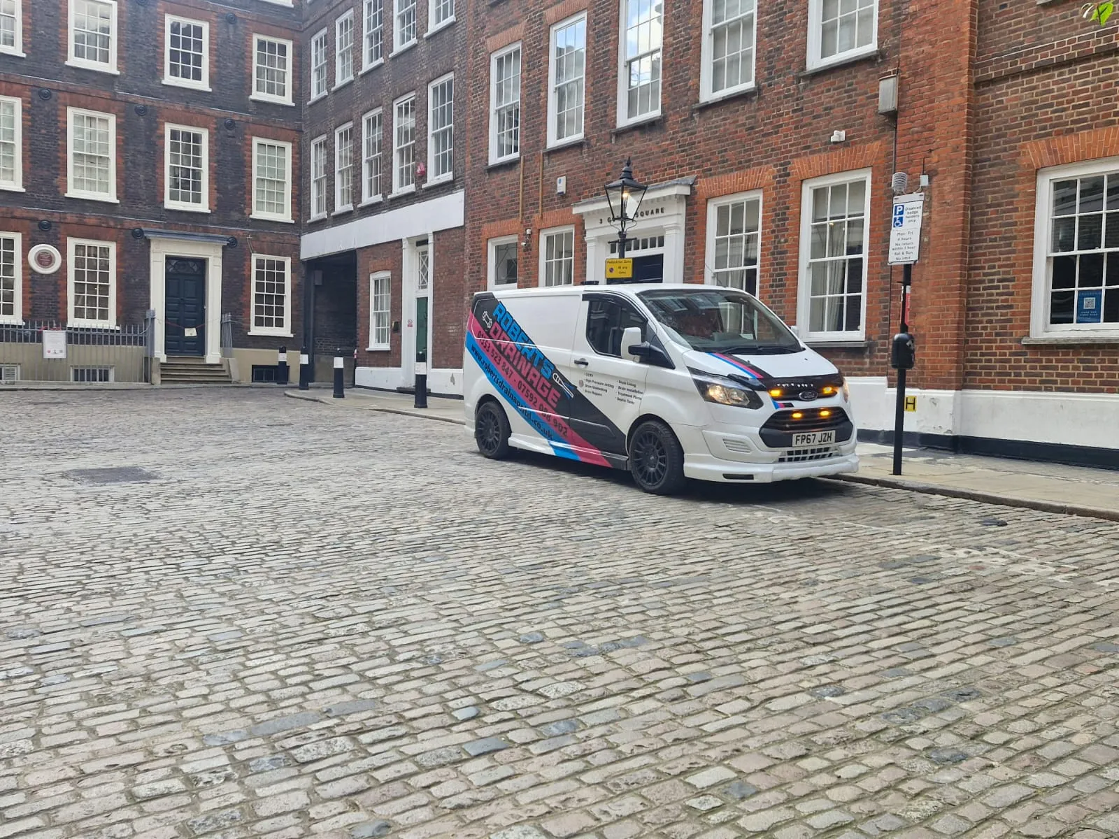Roberts Drainage Ltd service van parked on a cobblestone street in a city