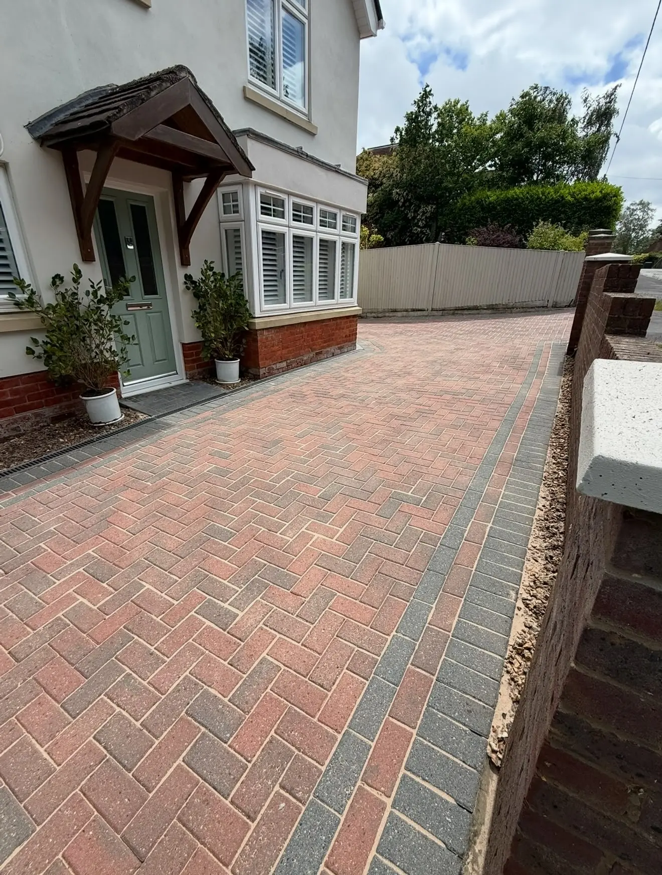 A clean red and grey block paving driveway in front of a house