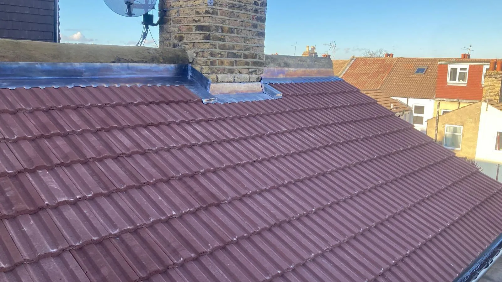 New lead flashing and lead apron installed around a brick chimney stack on a tiled pitched roof