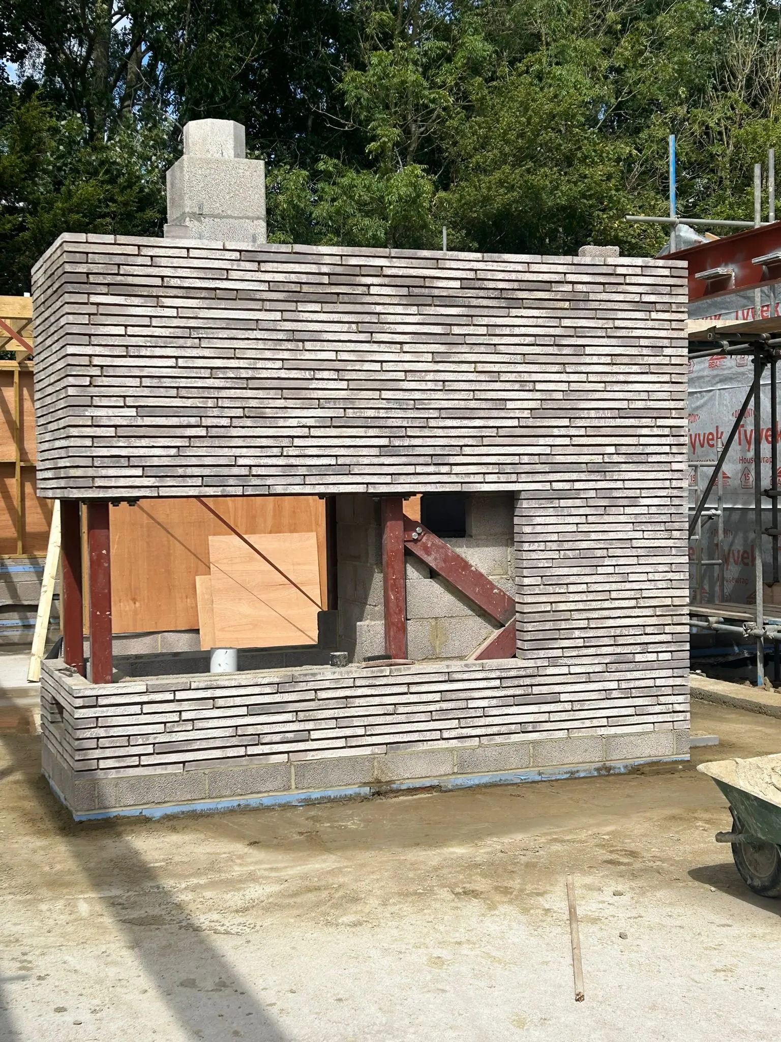 Modern grey brick fireplace under construction with steel beam supports