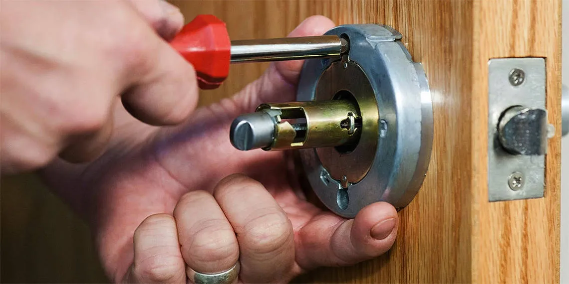 Close-up of a locksmith fitting a new lock or repairing an existing one on a wooden door.
