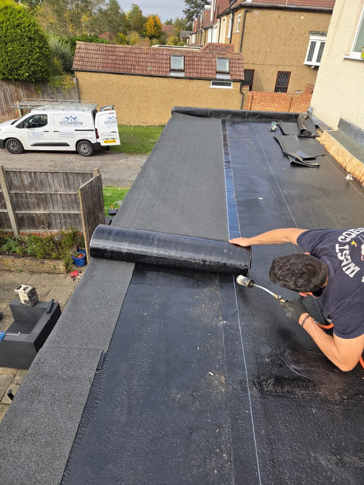 Professional roofer installing a torch-on felt flat roof on a domestic extension.
