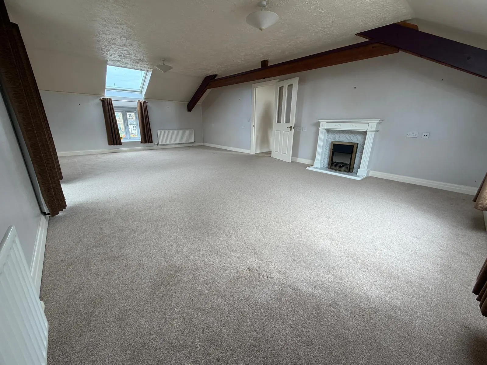 Large empty room with exposed beams and sloping ceiling in a Cotswold property, ready for spatial reconfiguration or bespoke joinery fit-out by Fortura Construction LTD.