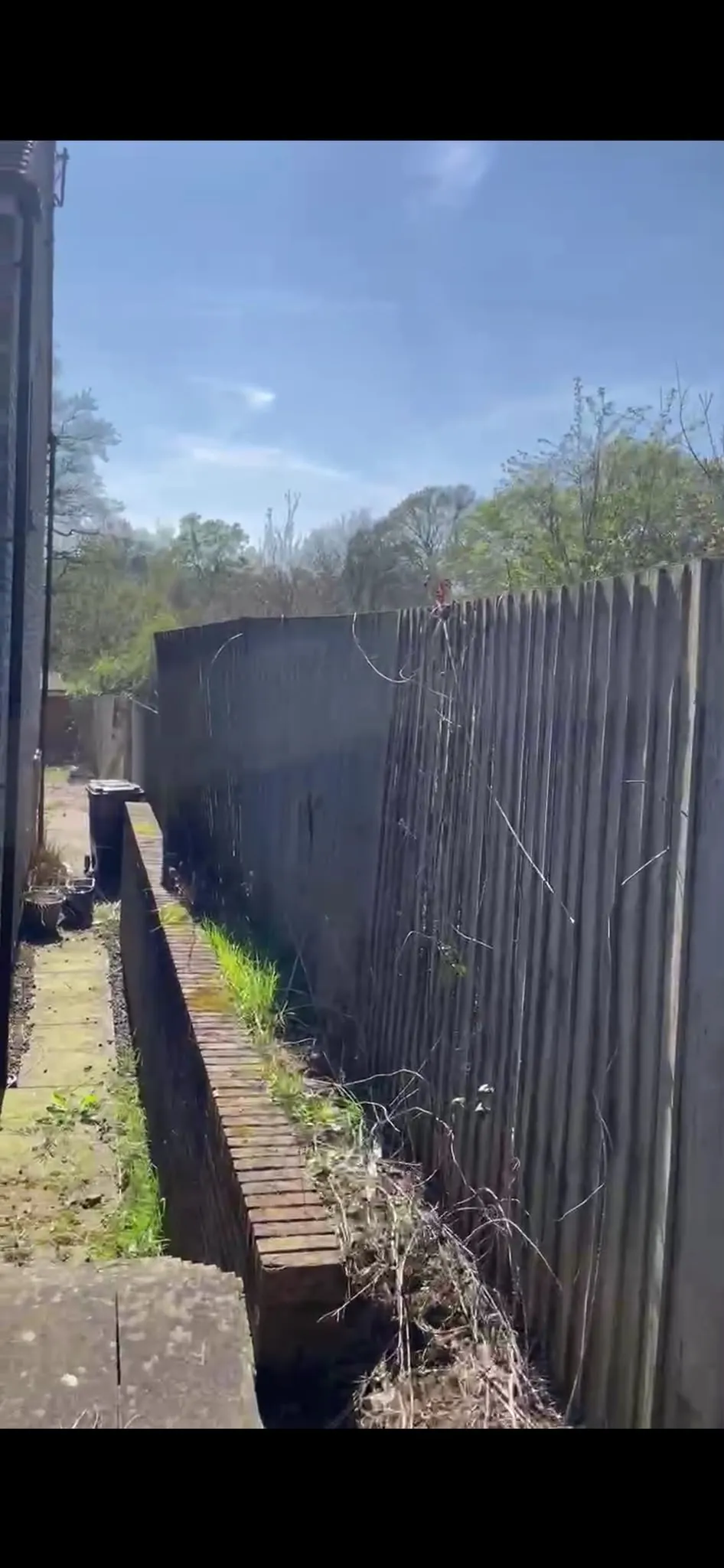 Leaning wooden featheredge fence in need of post repair in a residential garden
