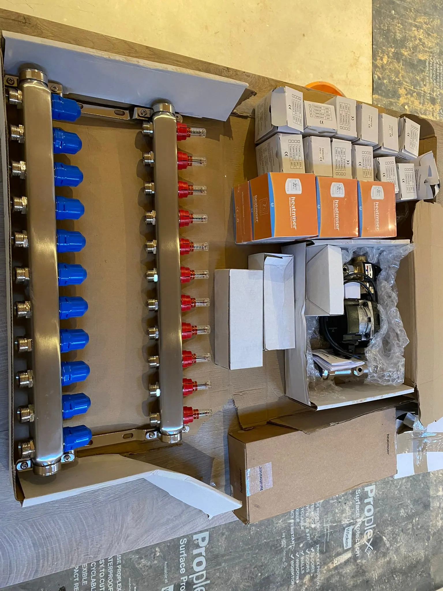 High-quality stainless steel underfloor heating manifold and Heatmiser smart thermostats ready for installation by Fact Services.