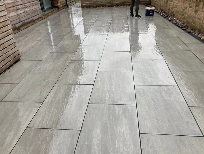 Newly installed, wet grey rectangular porcelain patio with a modern design.