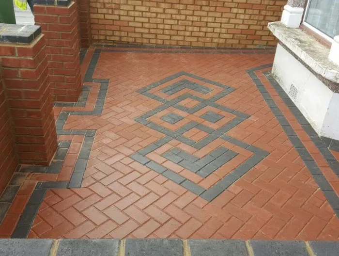 Newly installed block paved patio or pathway with a distinctive red and dark grey decorative pattern