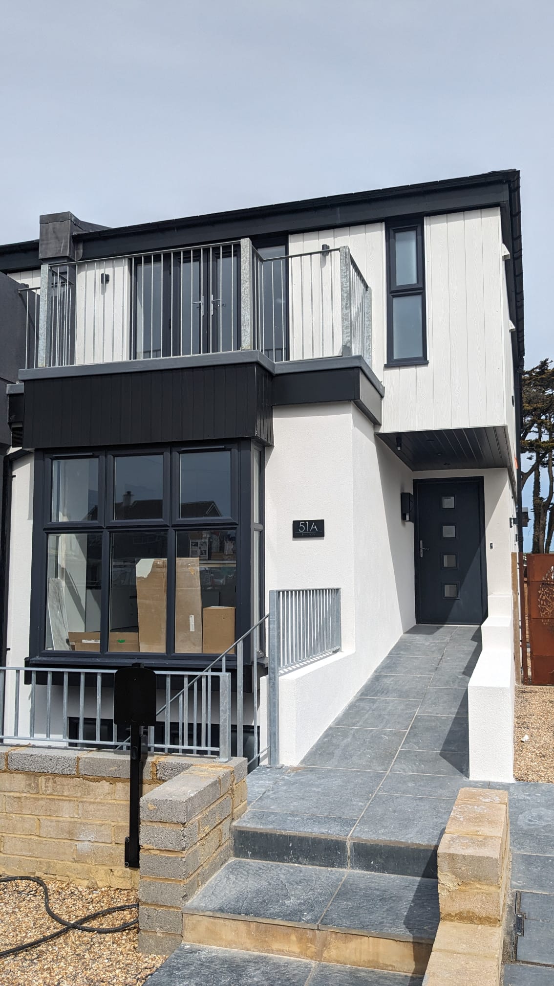 Modern house with white external rendering and black window frames in Southwick