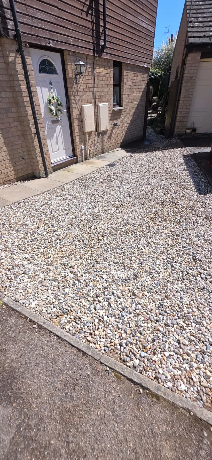 A clean shingle and gravel driveway installation for a home in Suffolk by FLEX PROPERTY SERVICES.