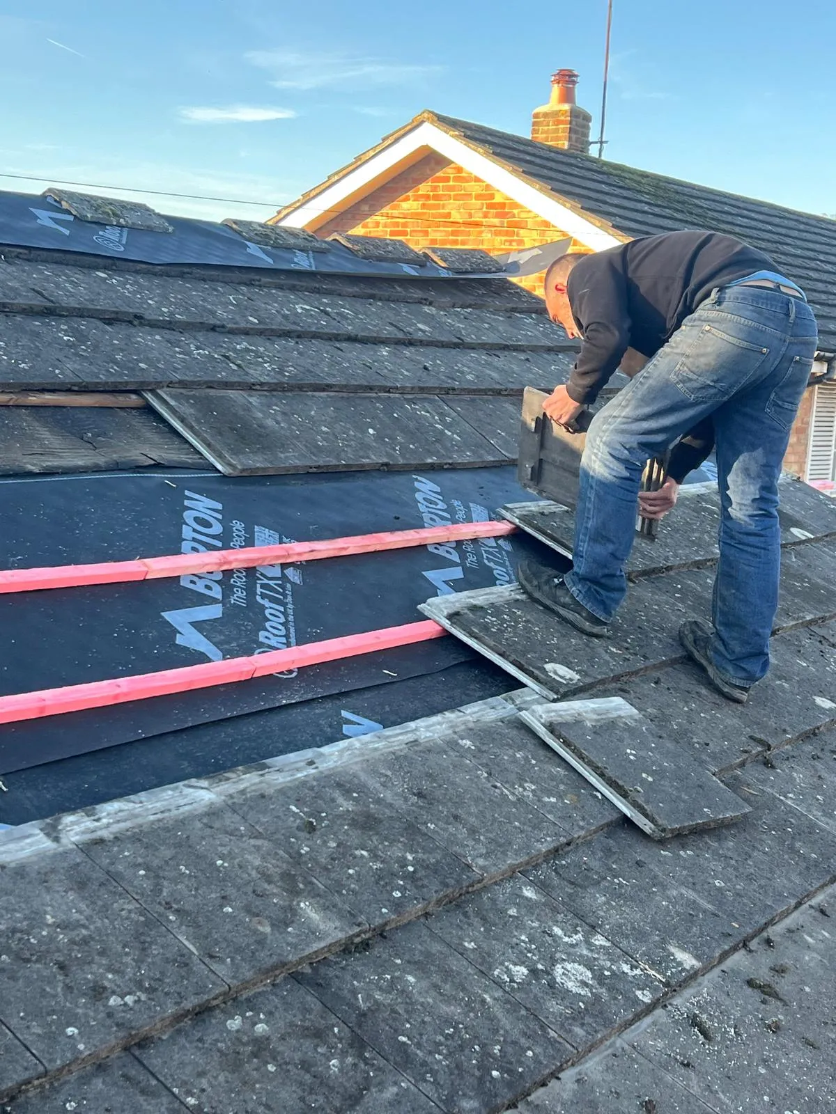 Professional roofer replacing concrete tiles on a pitched roof in West Malling, Kent.