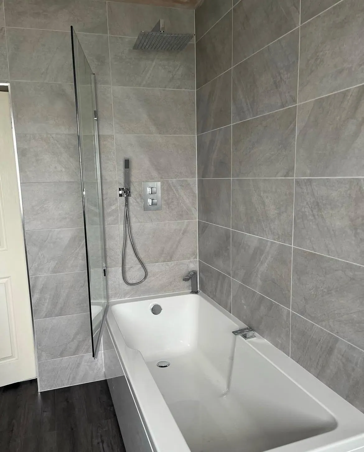 Modern bathroom installation in York featuring grey tiling and chrome shower fixtures.