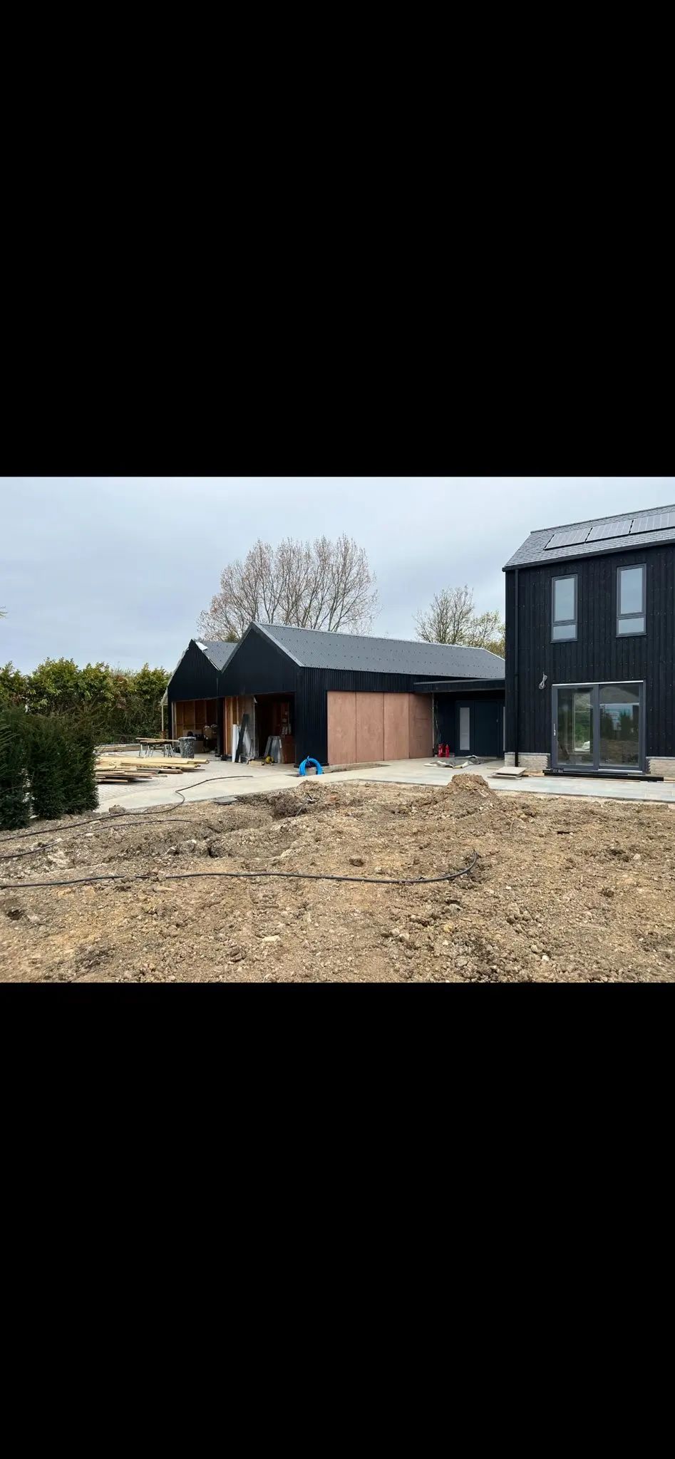 Modern black clad agricultural building under construction by ER3 Group LTD showing site preparation and groundworks