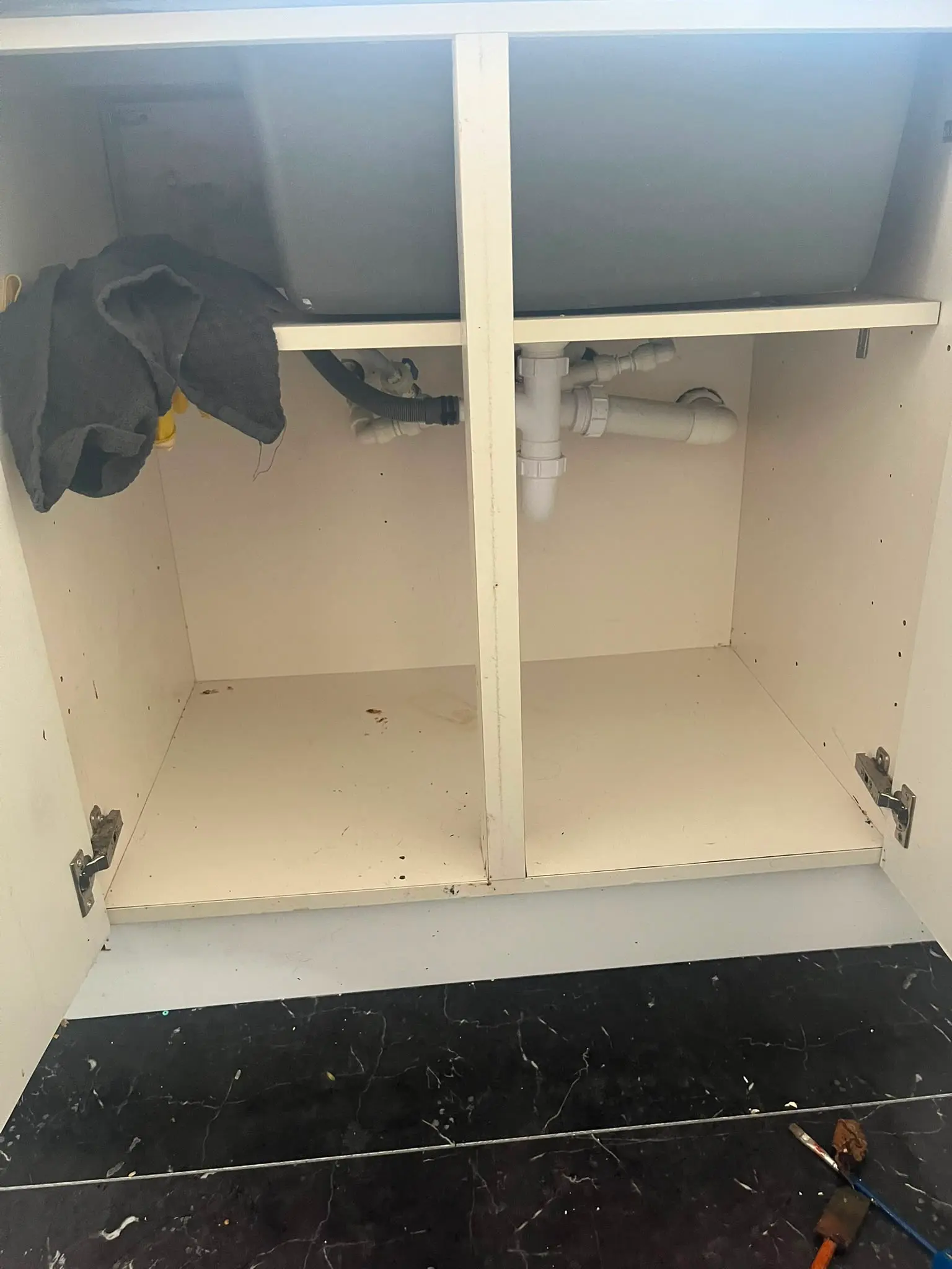 Under-sink waste pipes and plumbing inside a domestic kitchen cabinet