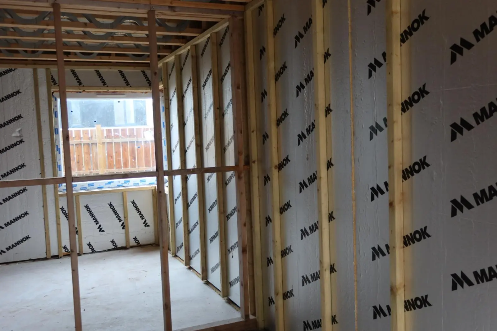 Rigid foil-faced internal wall insulation boards installed behind a new timber stud frame structure in a residential property.
