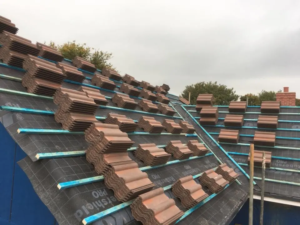 Stacks of new interlocking roof tiles placed on timber battens ready for installation
