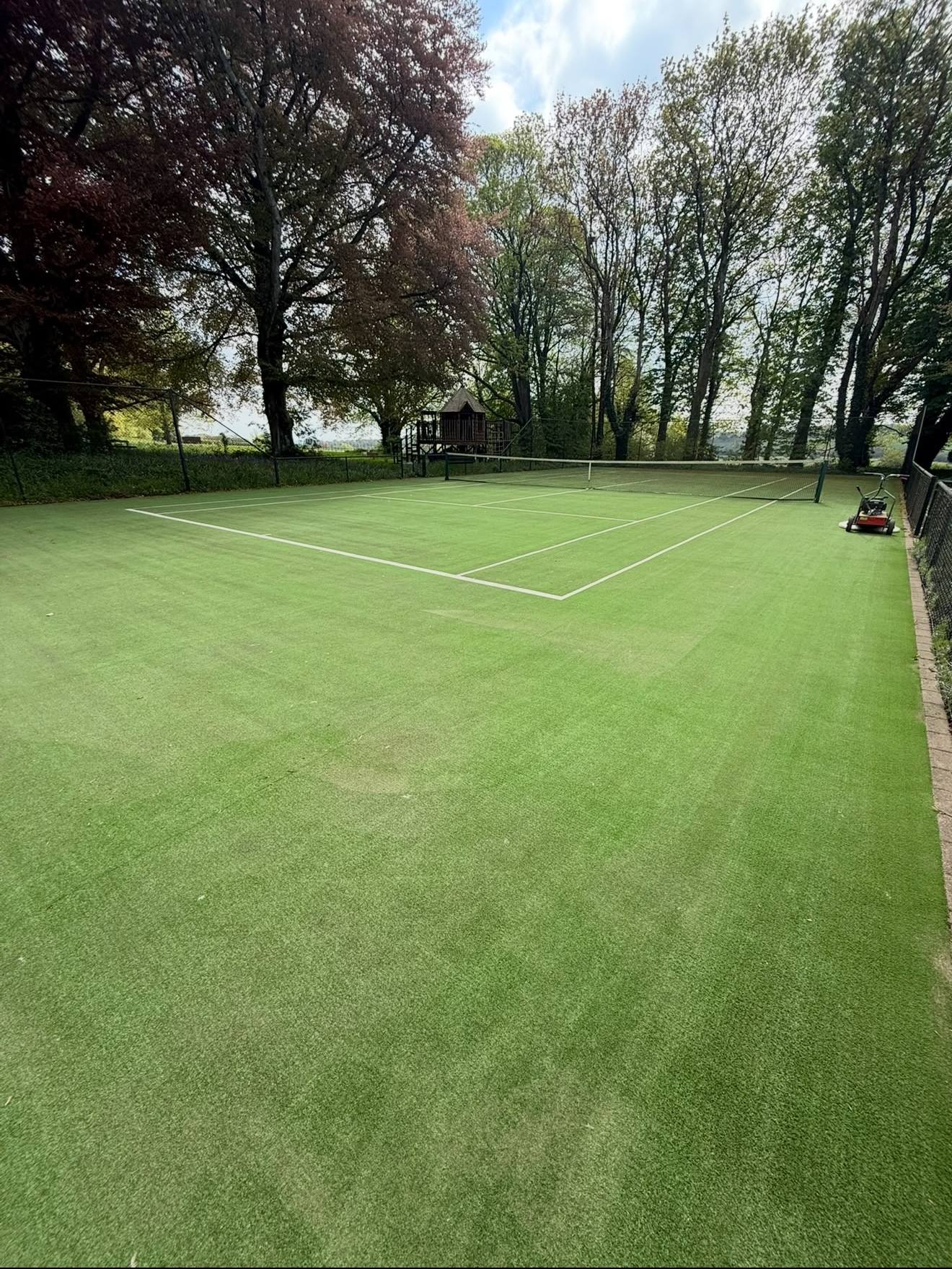 A freshly cleaned artificial grass tennis court ready for play