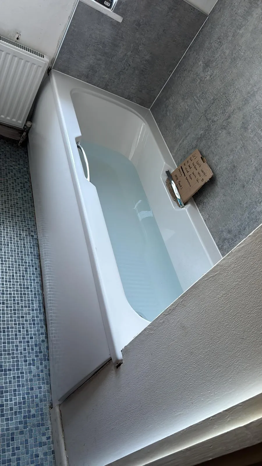 Professional plumbing or bathroom maintenance in Felixstowe showing a filled bathtub with a plumber's instruction note.