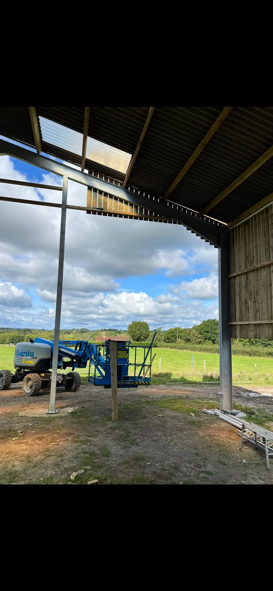 Steel frame erection and partial timber cladding in progress for a new agricultural farm shed by ER3 Group LTD, showing a cherry picker on site.