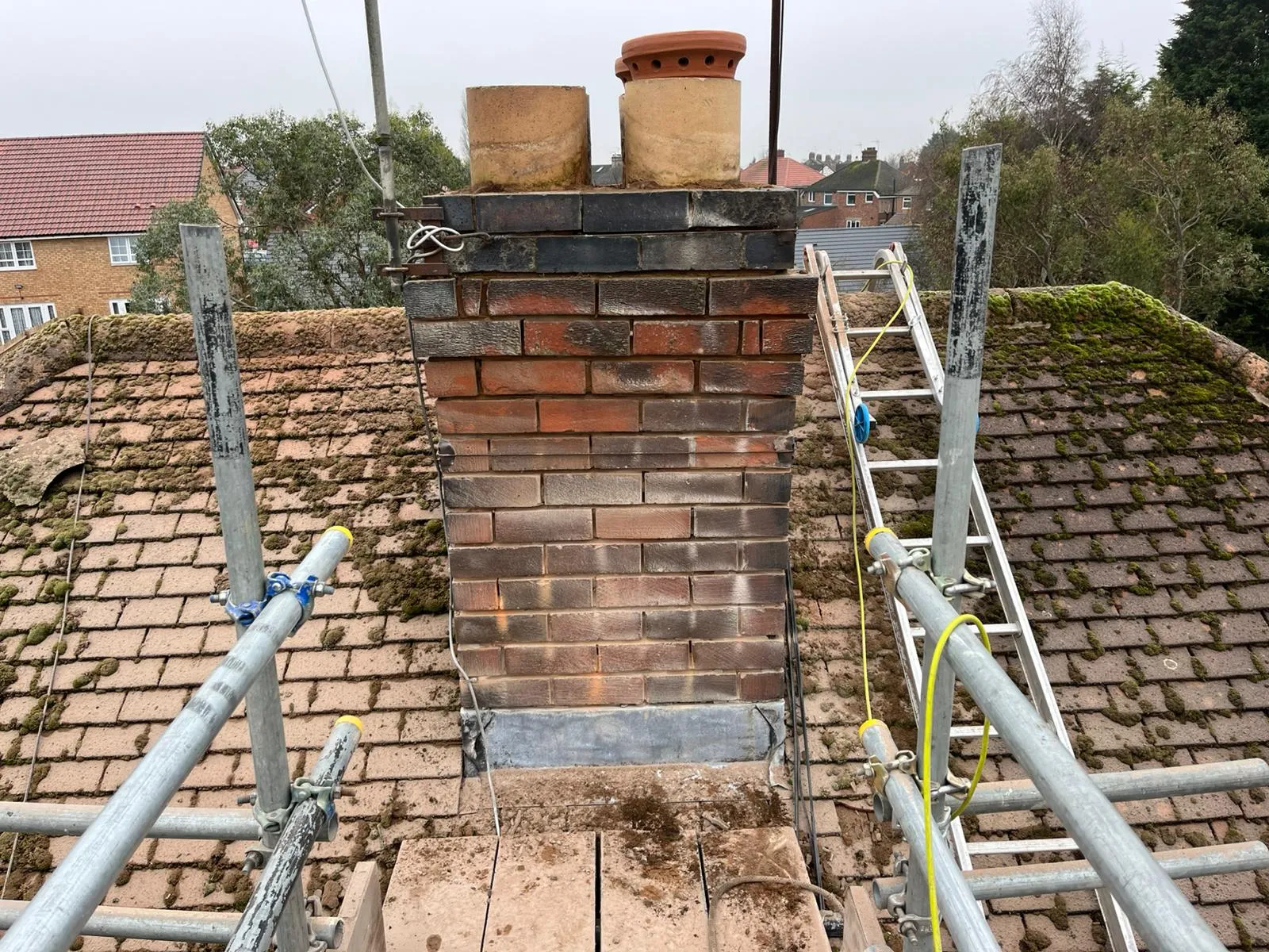 Professional chimney repairs and maintenance on a residential roof in Gloucestershire