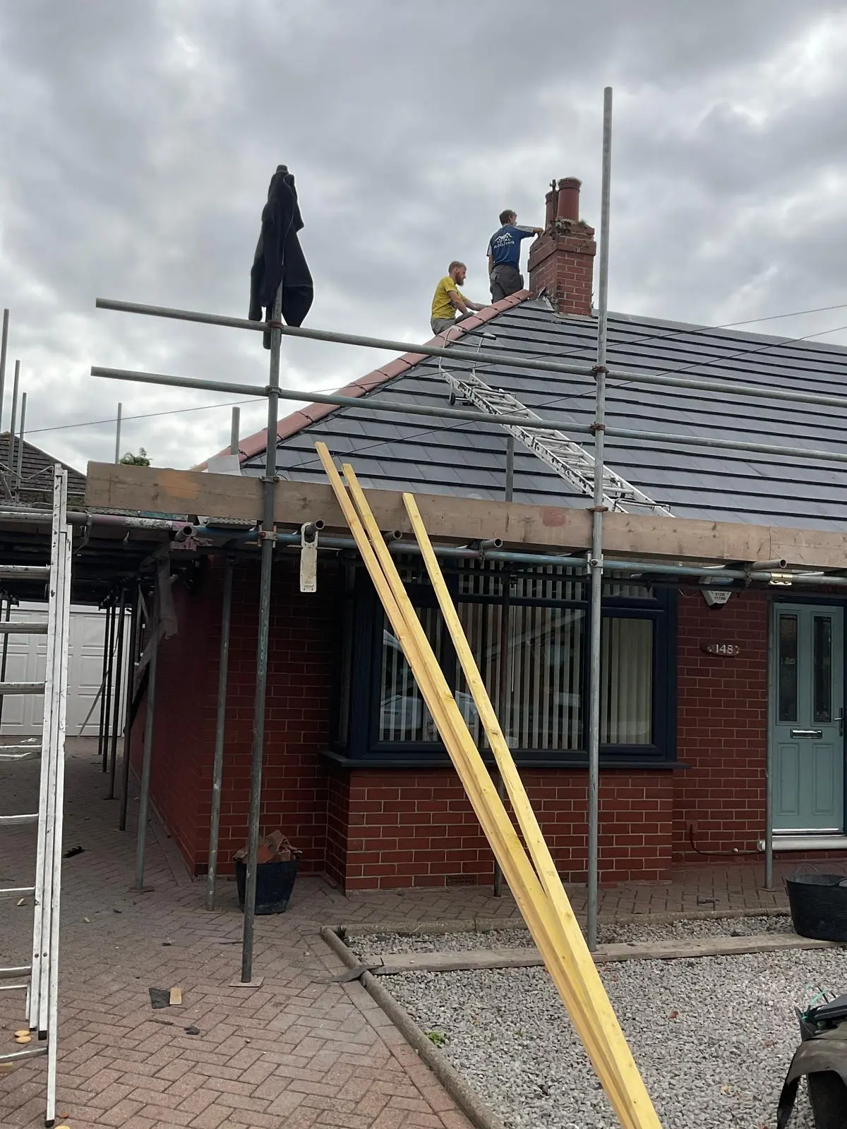 Professional roofers installing a new tiled roof with scaffolding on a house