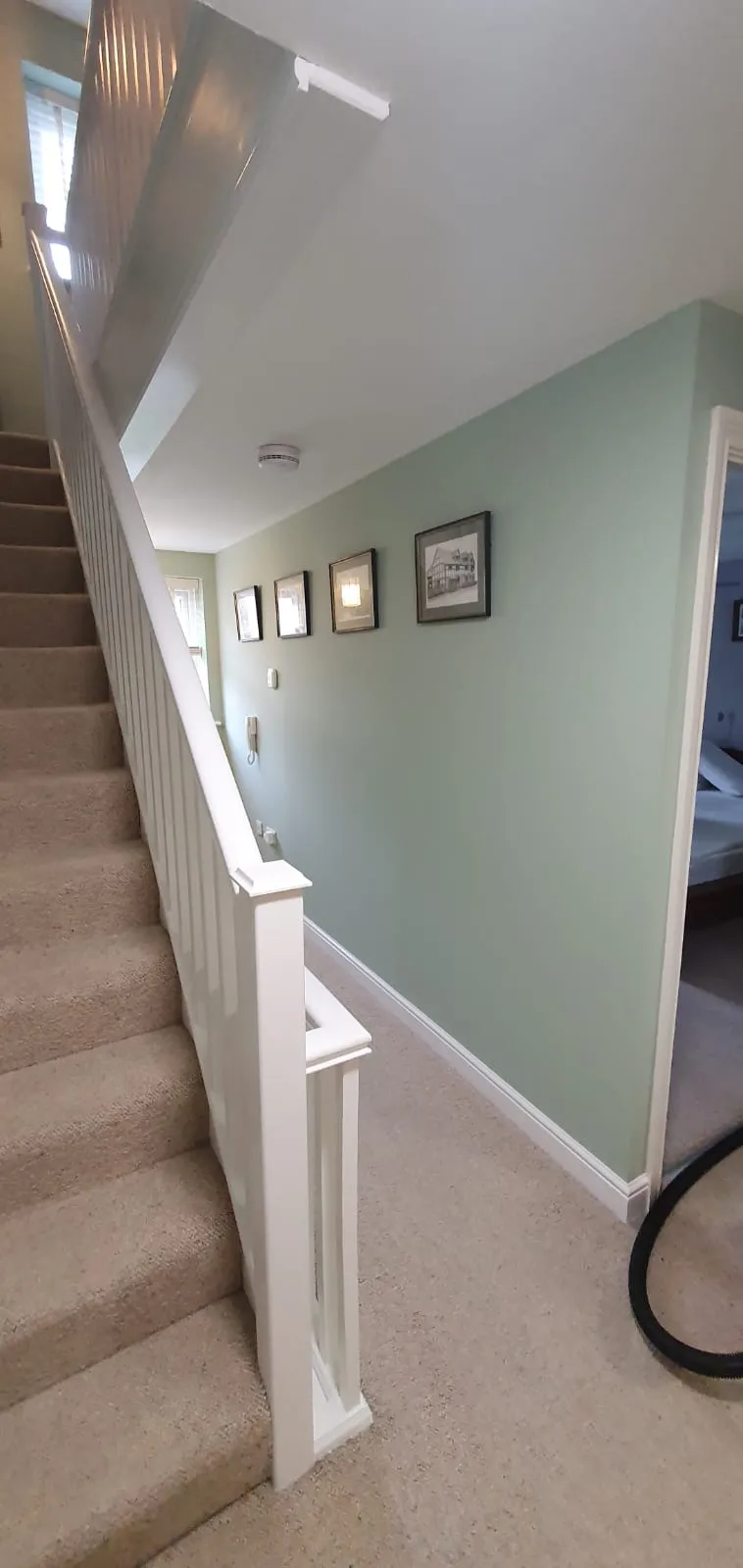 Interior painting and decorating of a hallway and staircase with sage green walls and white trim in a Suffolk home.