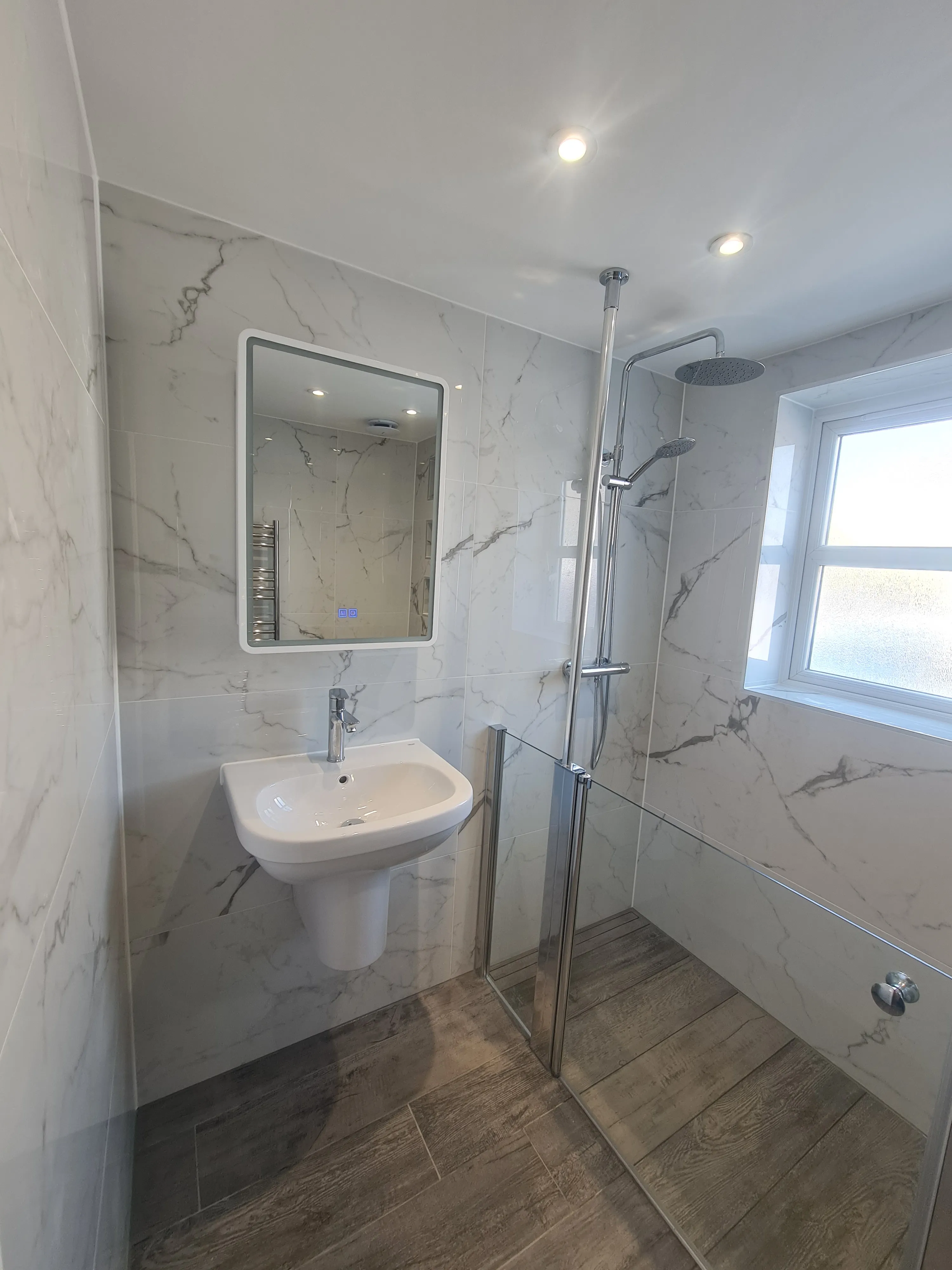 Bespoke luxury bathroom installation in Plymouth featuring marble tiling and a walk-in shower by Sands & Vossen.