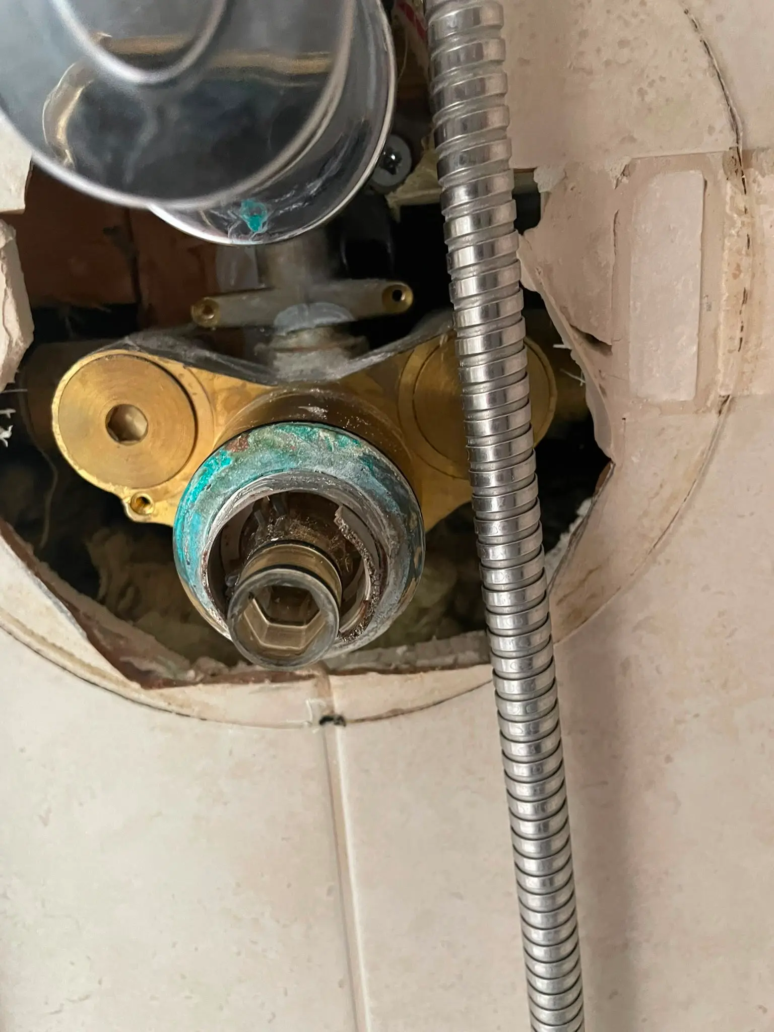 A close-up of a broken concealed shower valve requiring plumbing repair