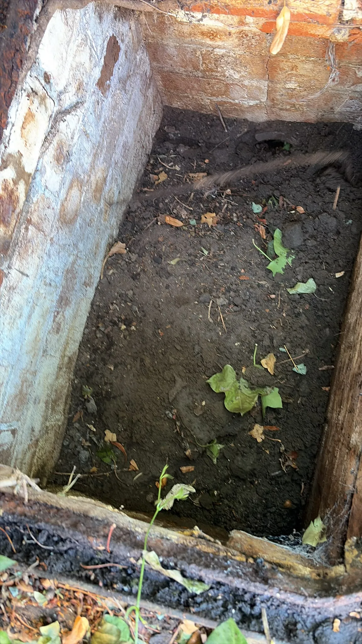 A heavily silted brick inspection chamber in need of clearance and repair in Slough