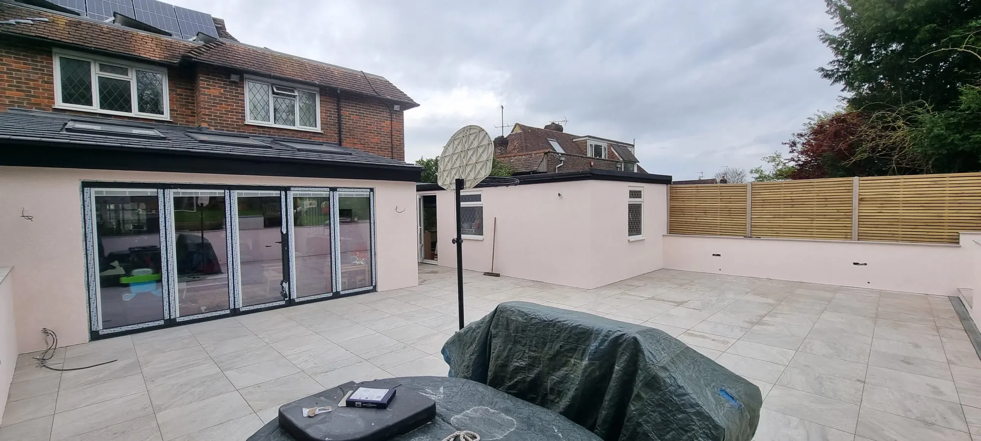 High-quality external rendering on a house extension and low garden walls surrounding a large tiled patio area.