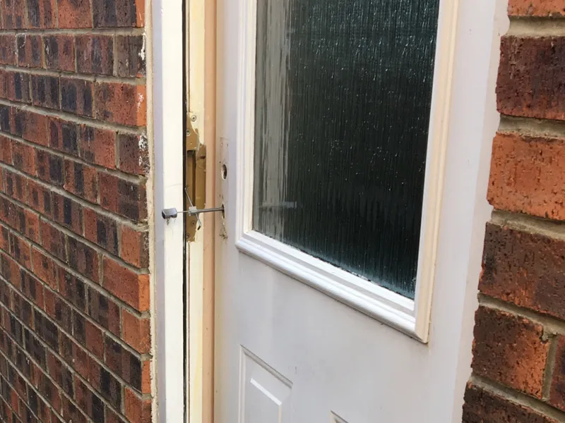 Locksmith repairing a multi-point lock mechanism on a white uPVC door
