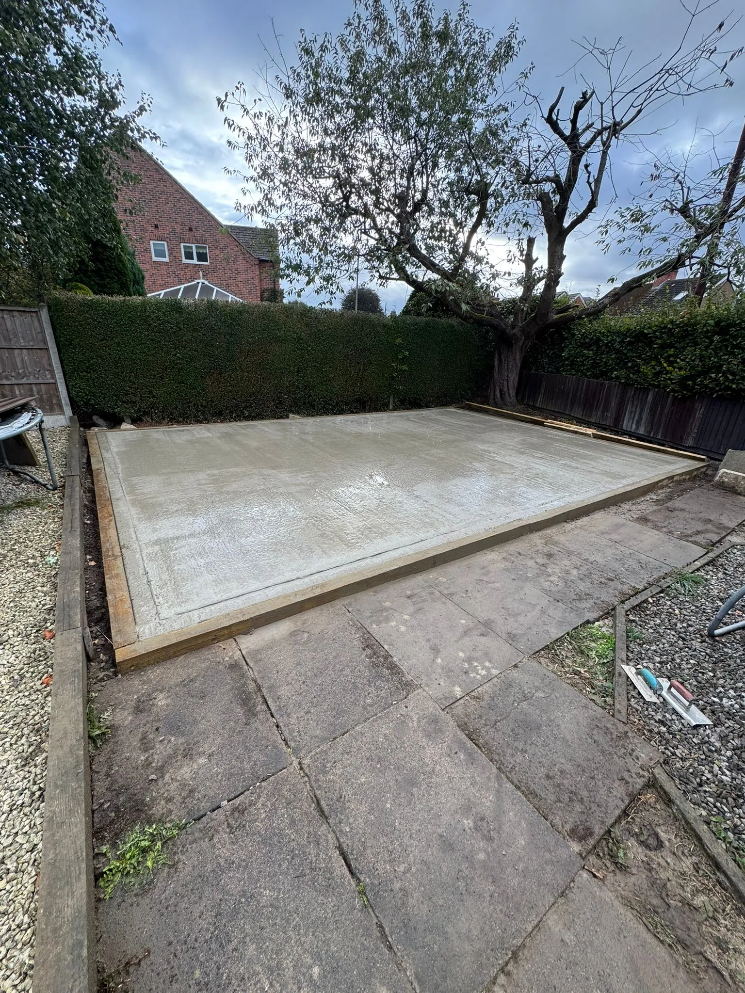 Freshly laid concrete slab foundation in a residential garden for a shed or outdoor structure.