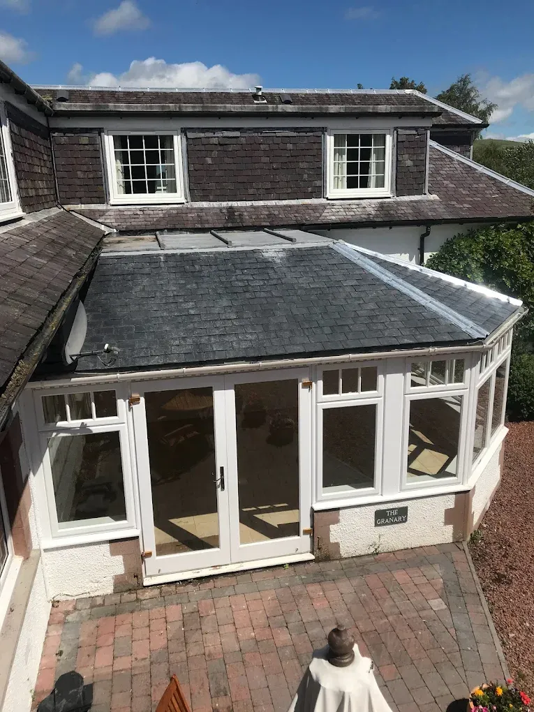High-quality slate roofing on a residential extension with white windows and a paved patio.