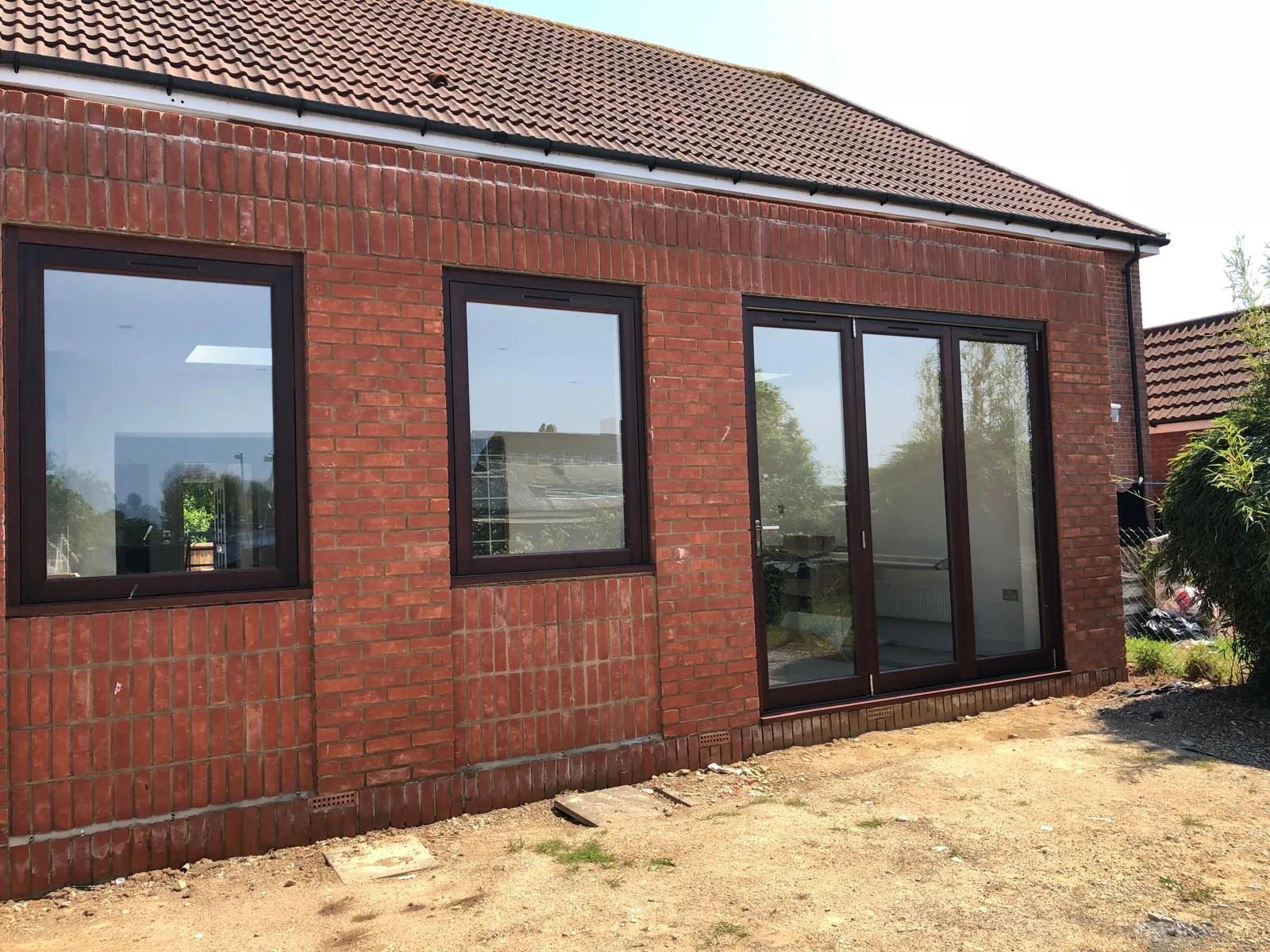 Newly constructed brick house extension with windows and bifold doors.