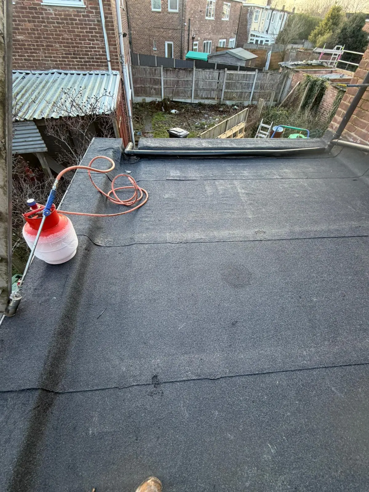 Torch-on felt flat roof installation showing gas torch equipment