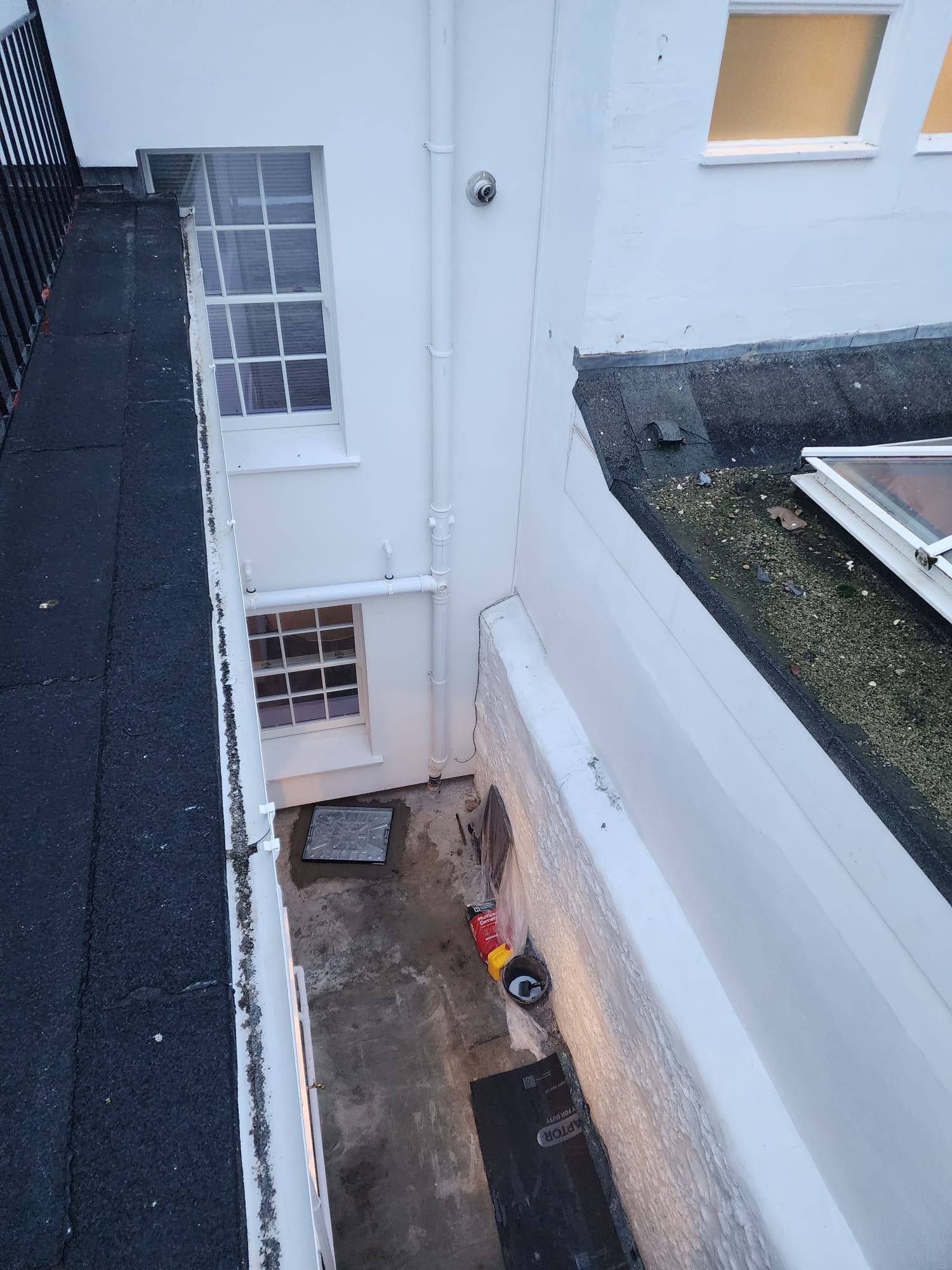 Freshly rendered white exterior walls and lightwell of a residential property.