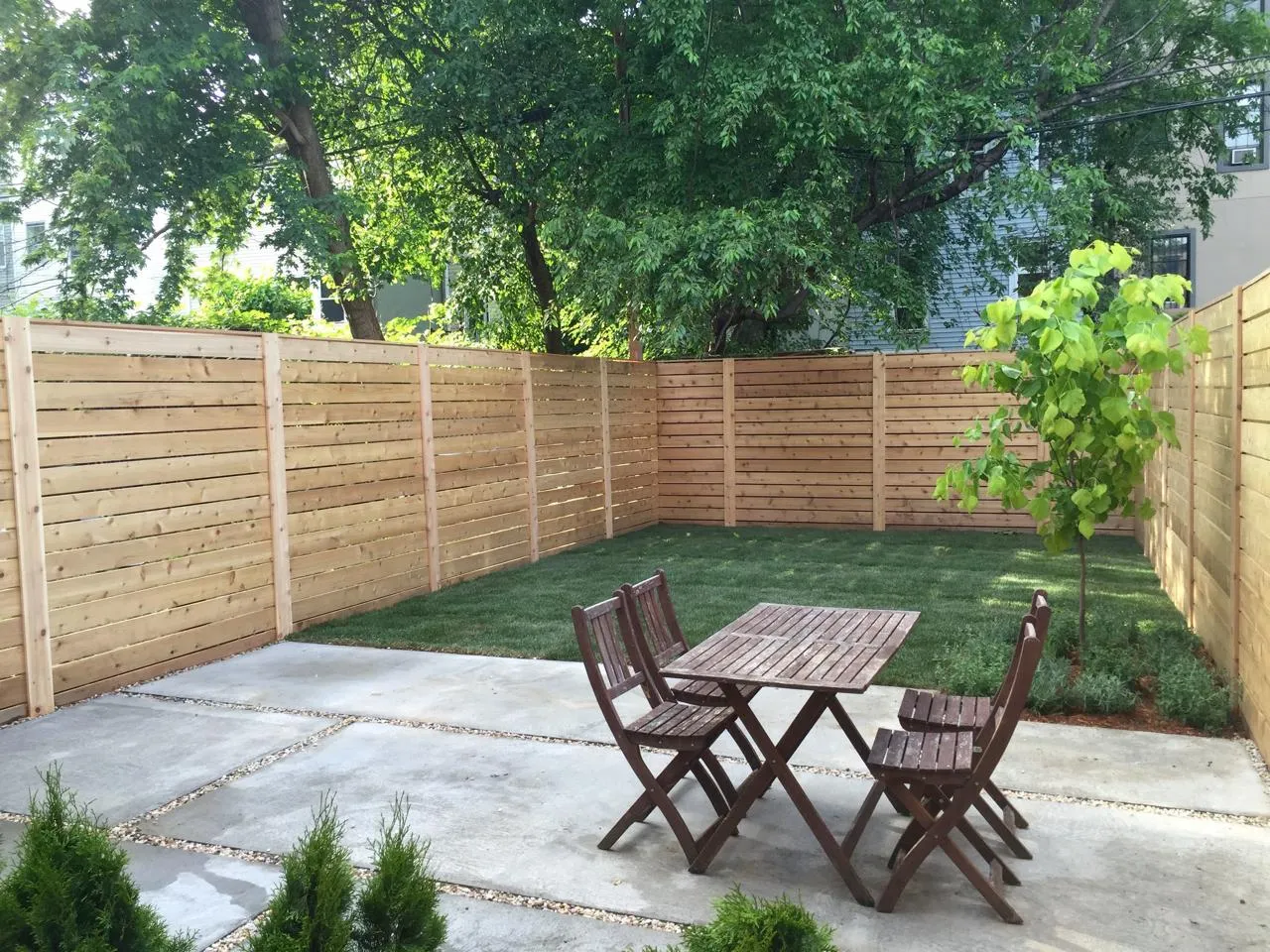 A professionally landscaped garden with horizontal timber fencing, a concrete patio, and a lawn area.