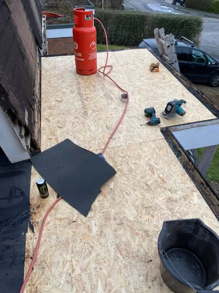 New OSB decking being installed on a flat roof during a roofing project.