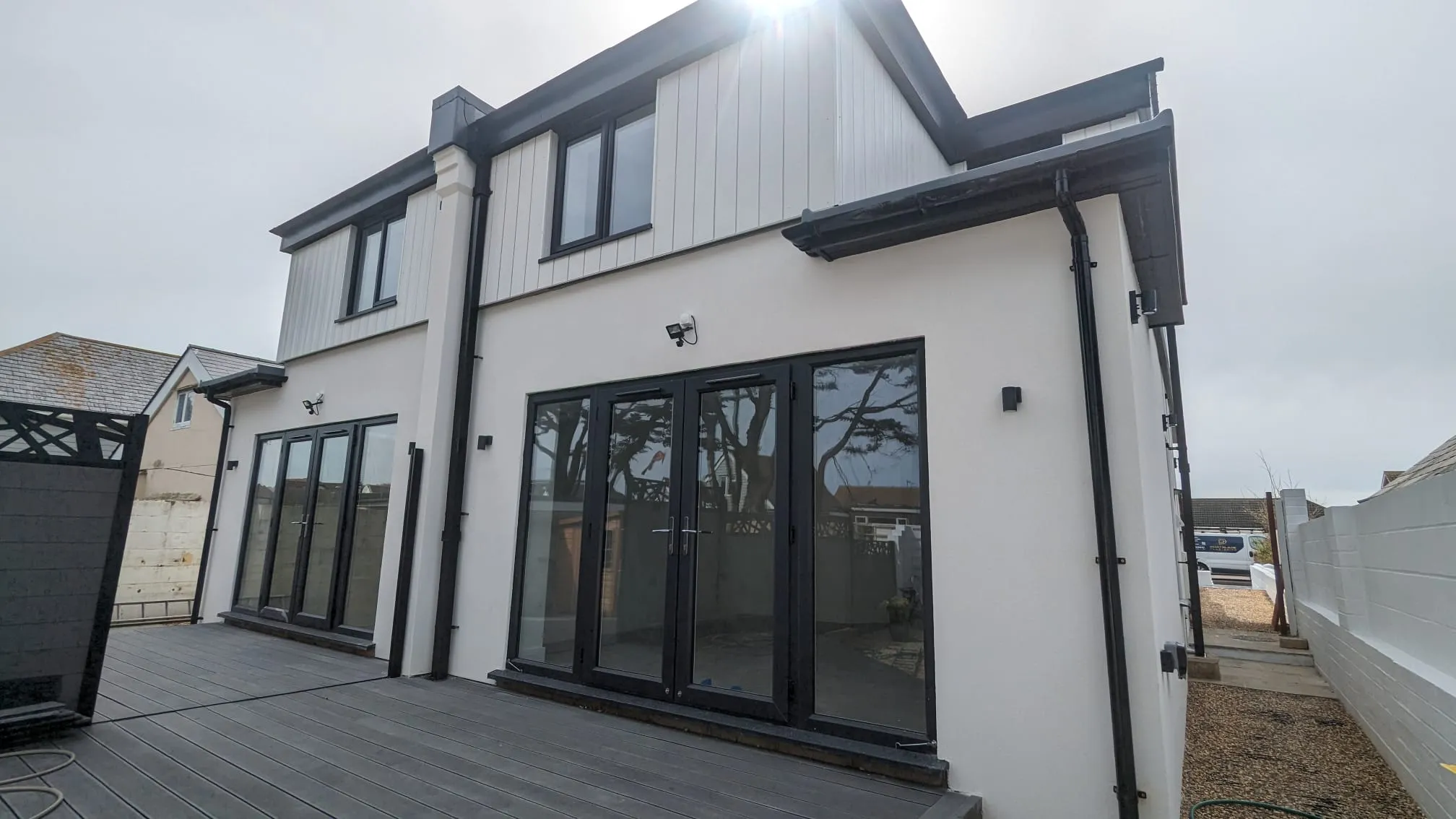 Professionally applied white external render on a modern home with black windows and decking.