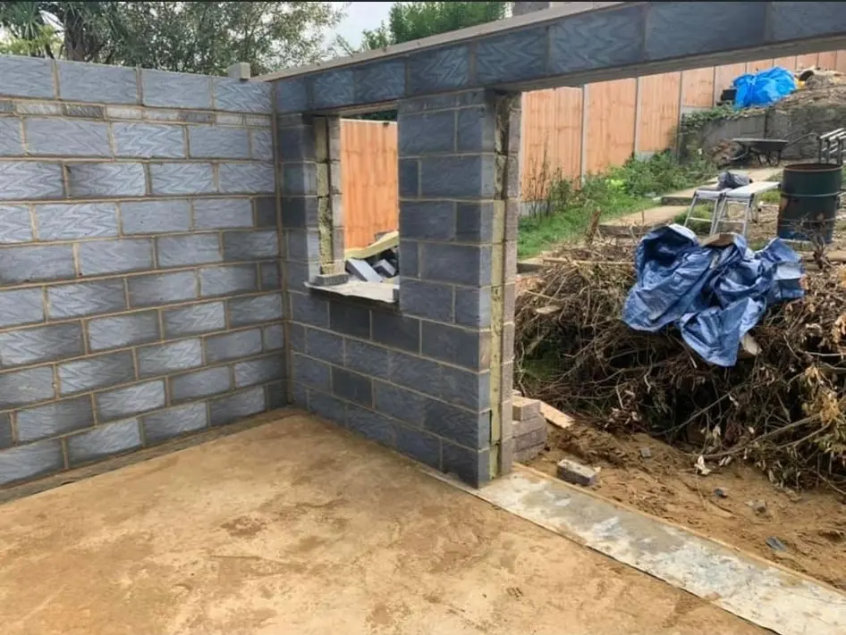 Partially constructed concrete block wall with window opening for a new house extension