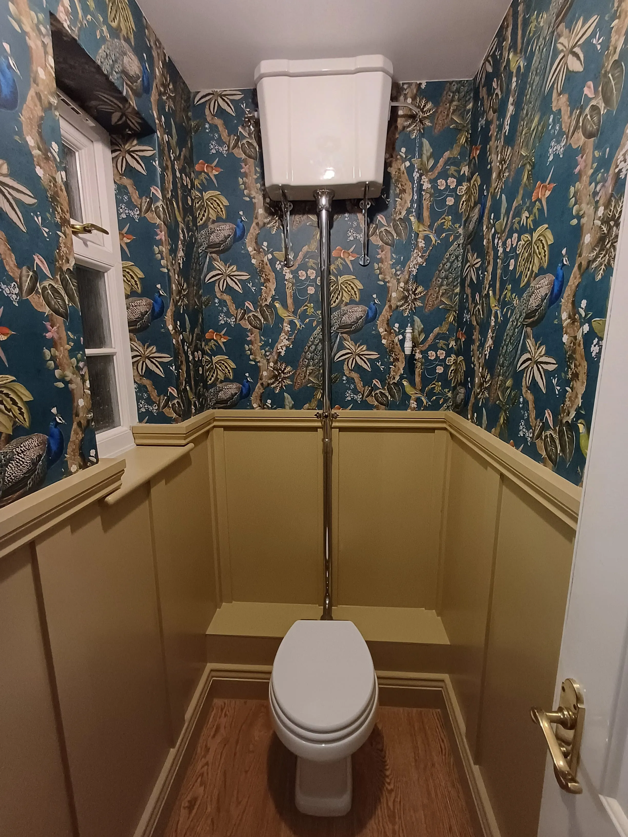 High-end bespoke cloakroom installation in a period property featuring peacock wallpaper and traditional gold panelling by Sands & Vossen.