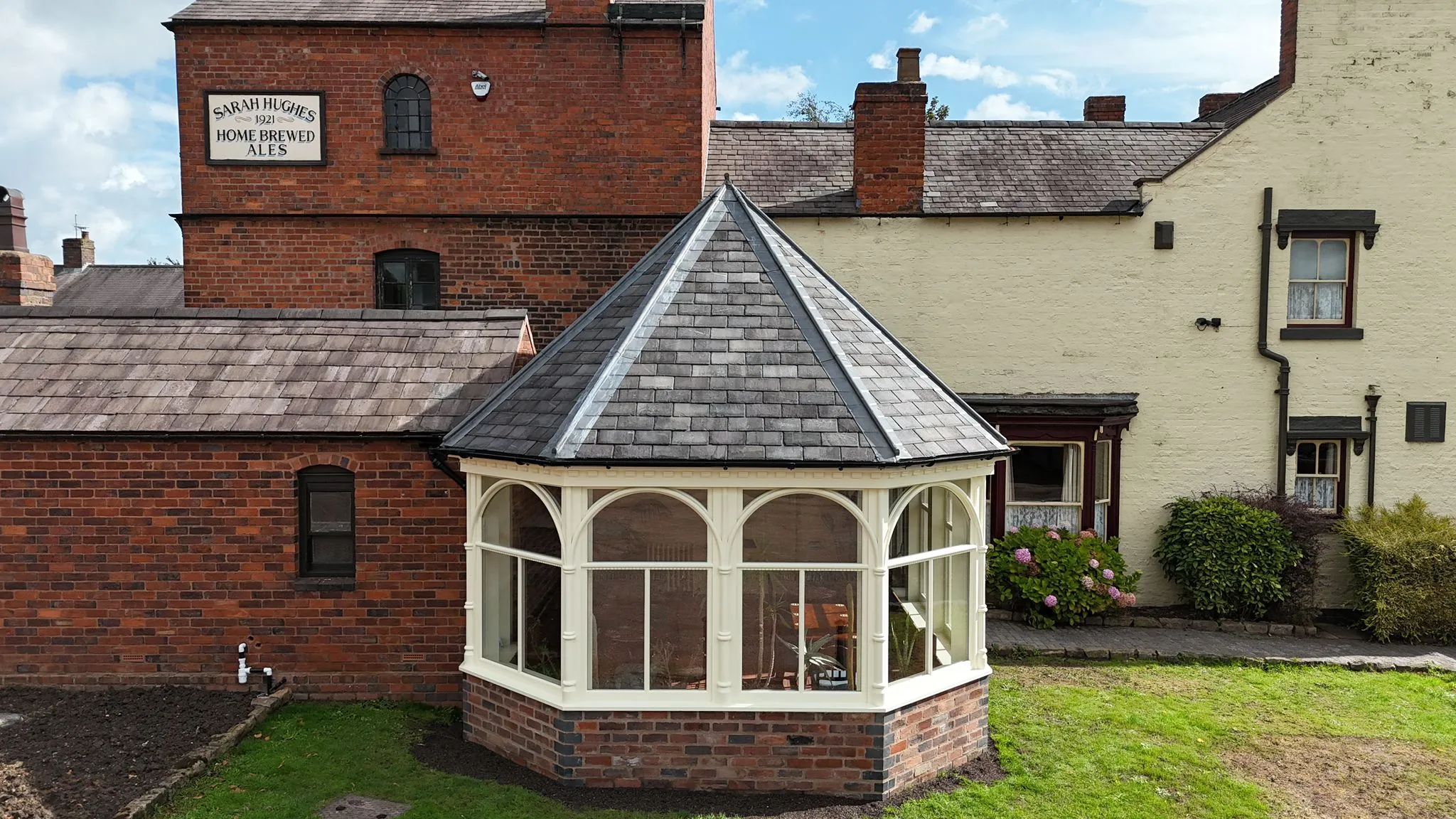 Exterior view of a newly built hexagonal orangery or garden room extension with a slate roof.